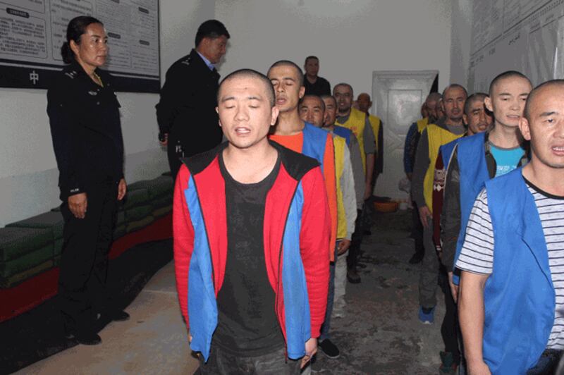 Police guard detainees as they appear to recite words or sing at the Tekes County Detention Center in northwestern China’s Xinjiang region in this image released on May 24, 2022.